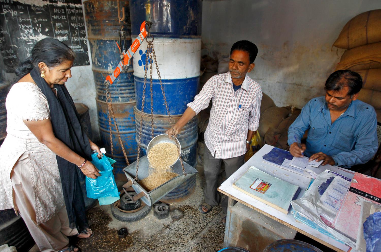 A woman who holds a BPL (Below Poverty Line) card buys wheat from a government-run ration shop in the western Indian city of Ahmedabad February 12, 2013.  Picture taken February 12, 2013.   To match INDIA-BUDGET/    REUTERS/Amit Dave (INDIA - Tags: BUSINESS FOOD SOCIETY POVERTY) - GM1E92F1NDT01