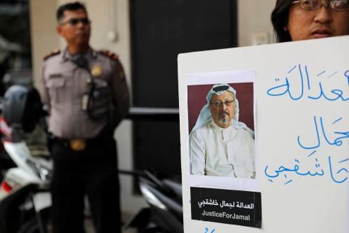 A policeman stands guard as an Indonesian journalist holds a placard during a protest over the disappearance of Saudi journalist Jamal Khashoggi in front of the Saudi Arabia embassy in Jakarta, Indonesia, October 19, 2018. REUTERS/Beawiharta - RC1787518E20