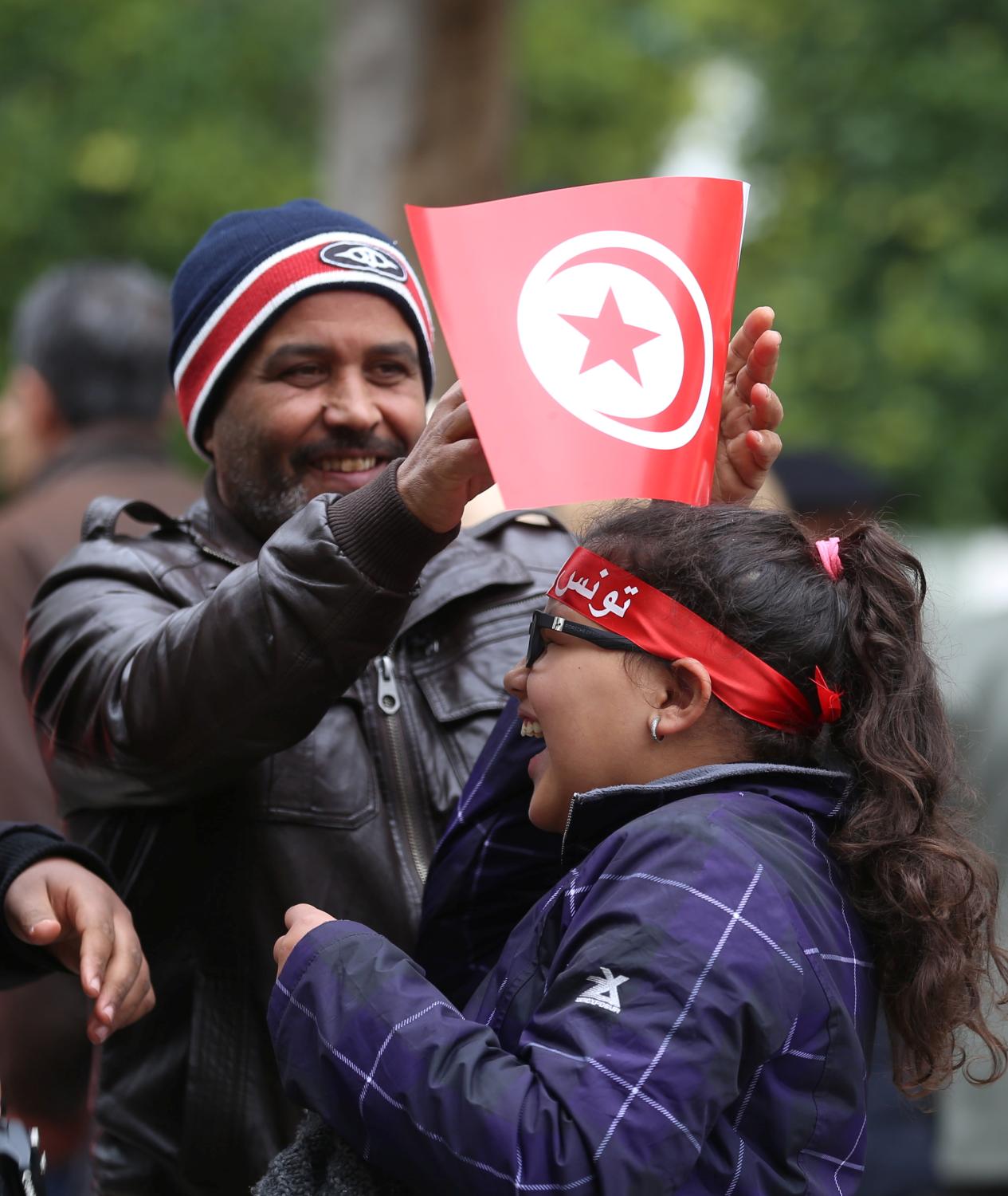 A man adjusts a flag for his daughter during celebrations marking the sixth anniversary of Tunisia's 2011 revolution in Habib Bourguiba Avenue in Tunis, Tunisia January 14, 2017. REUTERS/Zoubeir Souissi - RC192ECA71B0
