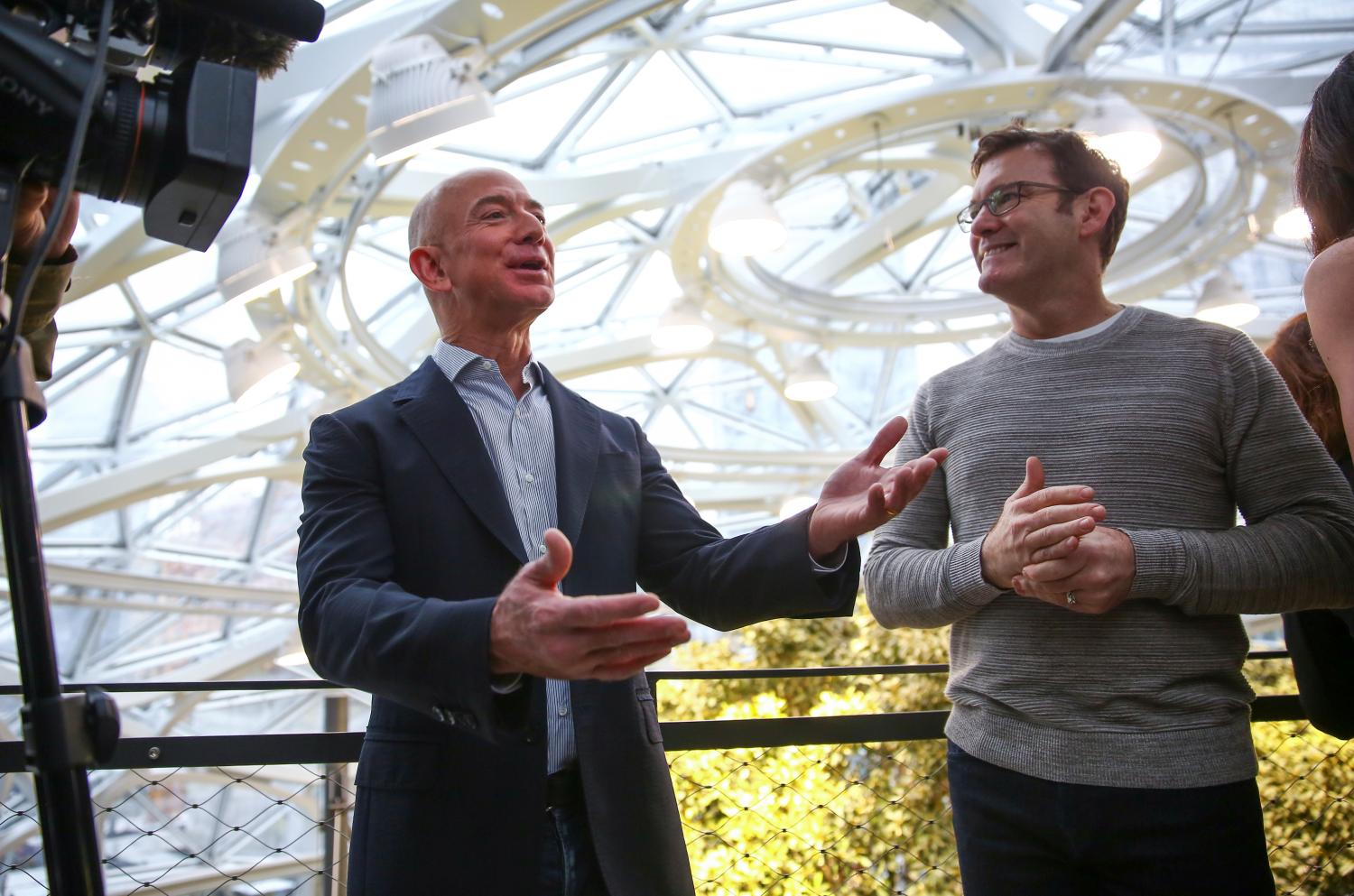 Amazon founder and CEO Jeff Bezos (L) answers a question from the media while getting a tour from Ron Gagliardo, senior manager of horticultural services for the Spheres, during the Amazon Spheres opening event at Amazon's Seattle headquarters in Seattle, Washington, U.S., January 29, 2018.  REUTERS/Lindsey Wasson - RC15E4464090