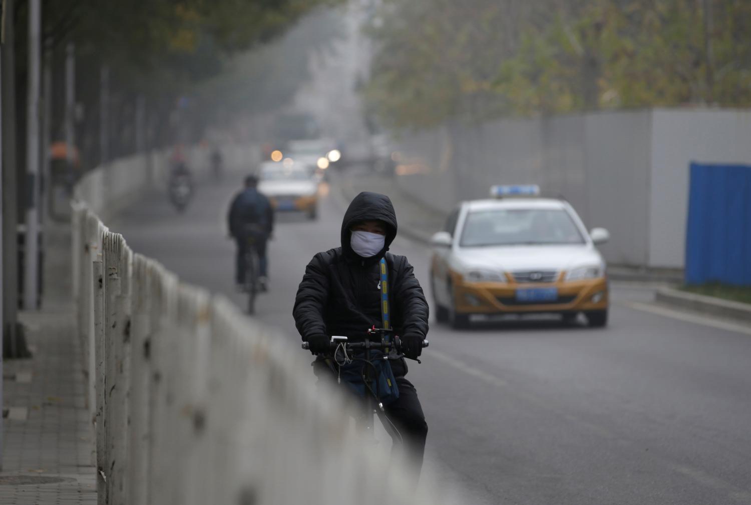 A man wearing a mask cycles on a road on a polluted day after a yellow alert was issued for smog in Beijing, China, November 14, 2018. REUTERS/Jason Lee - RC1FBD108B00