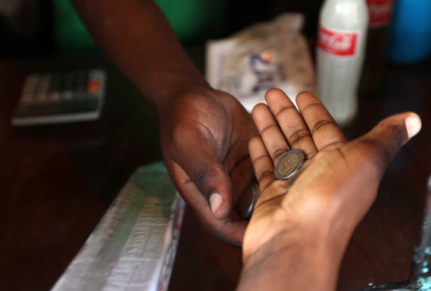 Money exchanges hands as a customer makes a purchase at a store in the sprawling Kibera slums in Kenya's capital Nairobi April 23, 2010. REUTERS/Noor Khamis (KENYA - Tags: SOCIETY BUSINESS) - GM1E65C0S7201