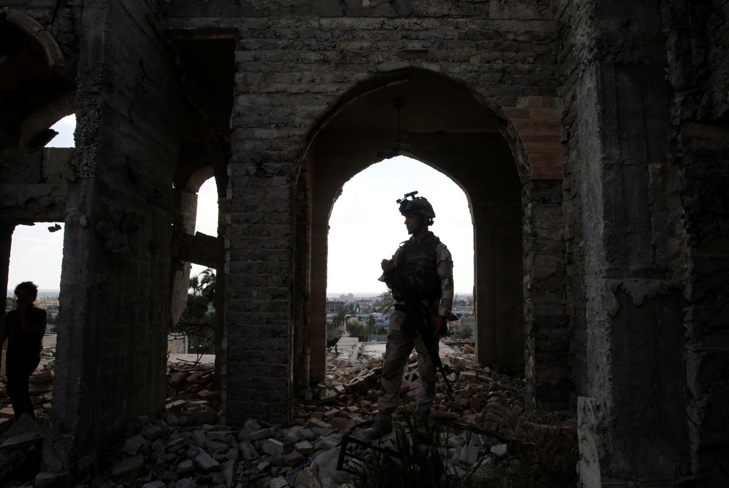 A member of the Iraqi security forces stands guard as Ameen Mukdad, a violinist from Mosul who lived under ISIS's rule for two and a half years where they destroyed his musical instruments, performs at Nabi Yunus shrine in eastern Mosul, Iraq, April 19, 2017. REUTERS/ Muhammad Hamed - RC167F7F0AE0