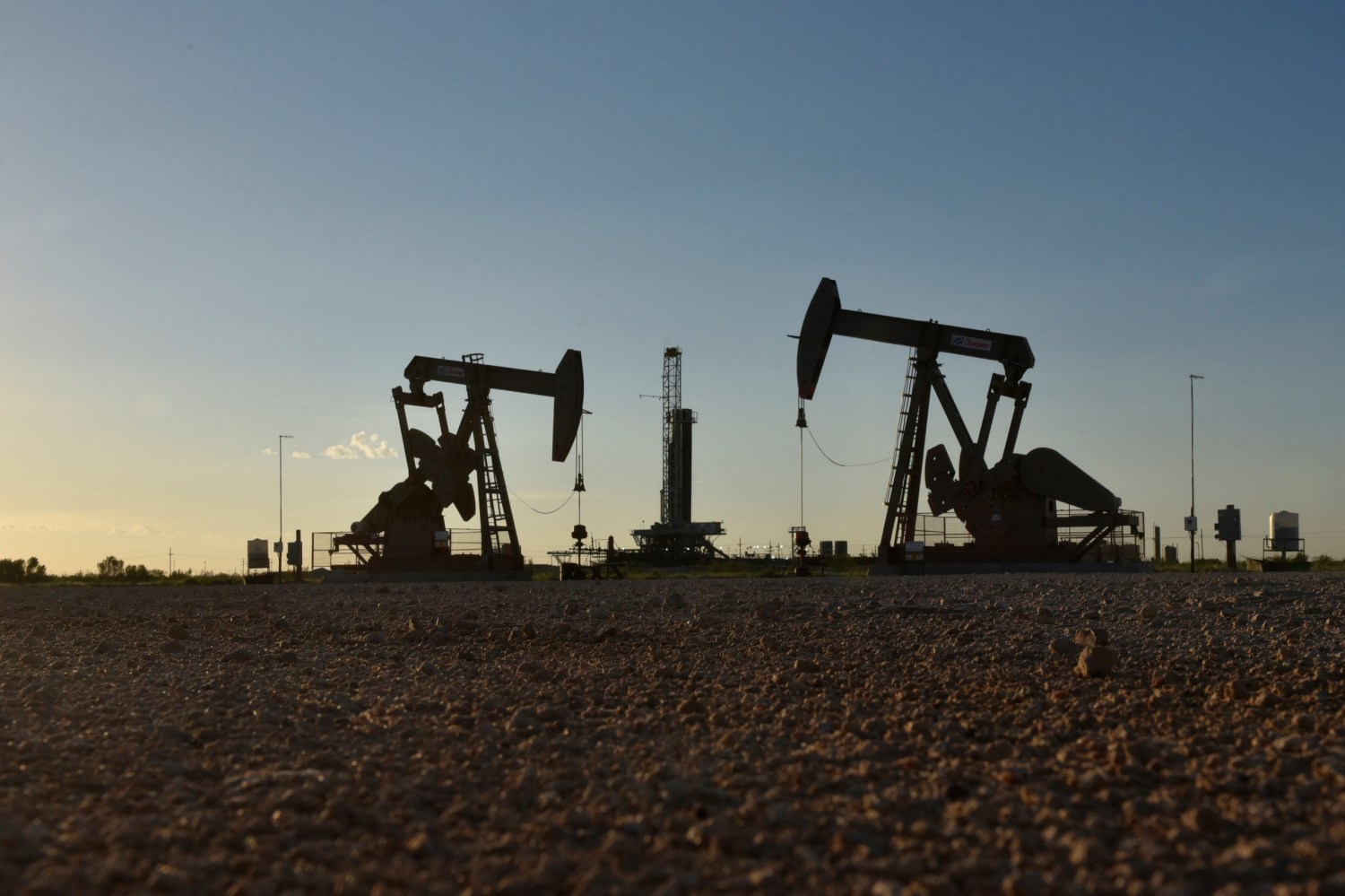 Pump jacks operate in front of a drilling rig in an oil field in Midland, Texas U.S. August 22, 2018. Picture taken August 22, 2018. REUTERS/Nick Oxford - RC1B5EE7E390