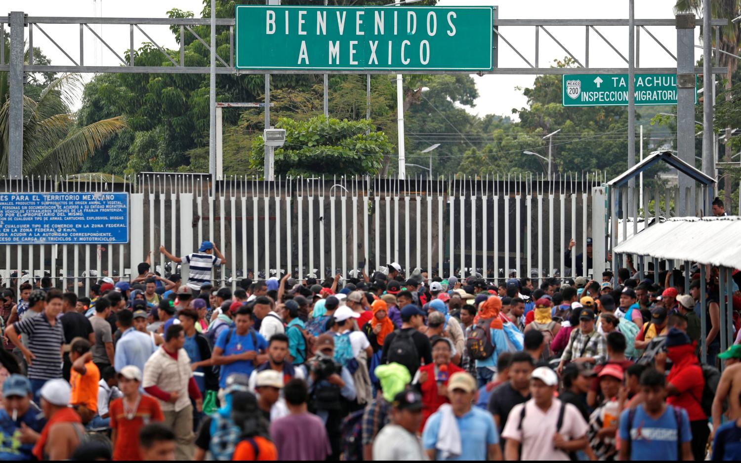 Central Americans, part of a caravan trying to reach the U.S., stand near the Mexican border gate on the bridge between Guatemala and Mexico.