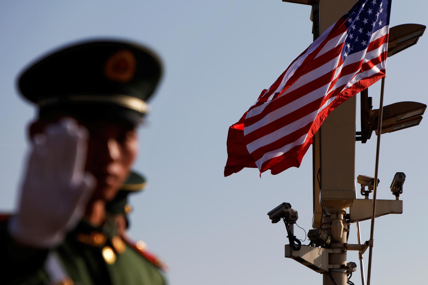 A paramilitary policeman gestures under a pole with security cameras, U.S. and China's flags near the Forbidden City ahead of the visit by U.S. President Donald Trump to Beijing, China November 8, 2017. REUTERS/Damir Sagolj - RC194AD3C400