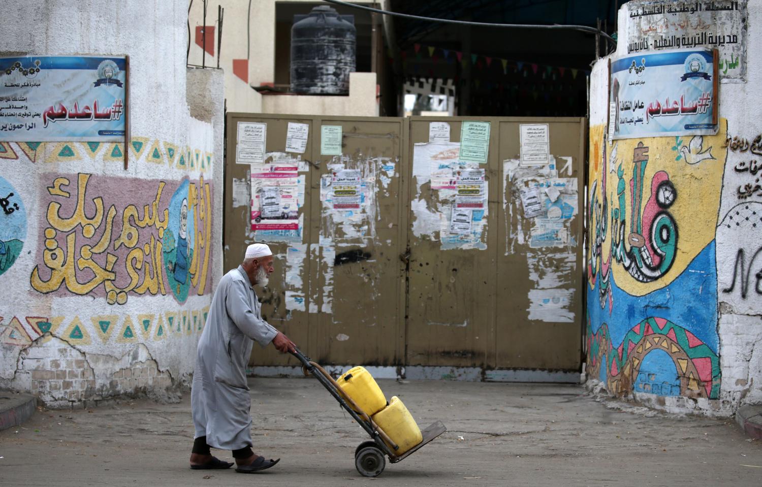 A Palestinian man pushes a cart past a closed school during a general strike in support of an Israeli-Arab protest against Israel's Nation State Law, in Khan Younis in the southern Gaza Strip October 1, 2018. REUTERS/Ibraheem Abu Mustafa - RC1E115E2E90