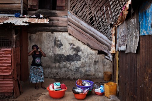 A woman combs her hair in the back courtyard of a traditional colonial-era Board House dating back about a century in the Murray Town neighbourhood of Sierra Leone's capital Freetown April 28, 2012.  Board Houses are a reconstruction of cabin-like structures built in the 18th century on the American eastern seaboard.  There were some modifications though, notably a three-foot base layer of porous local stone (seen here) that helped anchor the house down during Sierra Leone's torrential wet season.  Picture taken April 28, 2012.  REUTERS/Finbarr O'Reilly (SIERRA LEONE - Tags: SOCIETY)   ATTENTION EDITORS - PICTURE 06 OF 29 OF PACKAGE 'FREETOWN - FADING ARCHITECTURE' - GM1E8531KOM01