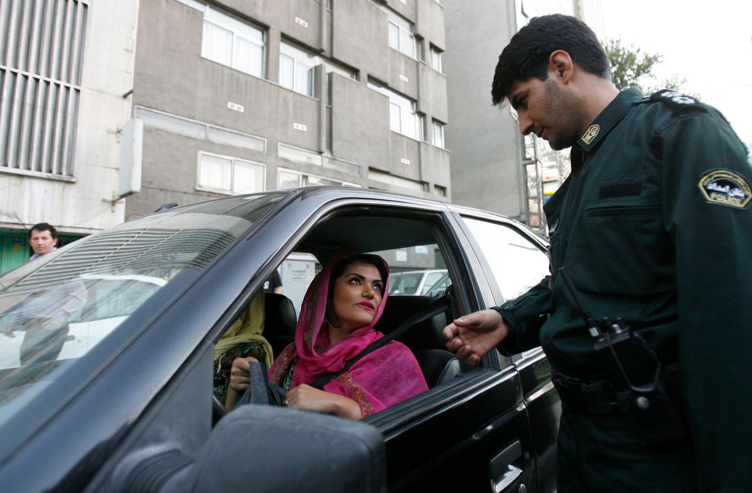 A policeman asks a woman wearing bright coloured clothes for her identification papers at a morals police checkpoint in Tehran June 16, 2008. Iranian police have launched a more extensive crackdown on "social corruption" such as women flouting Islamic dress codes, the Farhang-e Ashti newspaper reported on Monday. The authorities usually launch crackdowns before the hot summer months when women like to wear lighter clothing such as calf-length pants and brightly coloured scarves pushed back to expose plenty of hair. Picture taken June 16, 2008.  REUTERS/Stringer (IRAN) - GM1E46H16MY01