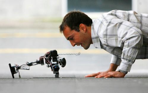 Imformatics PHD student Sebastian Bitzer performs push up exercises with a programmed Kondo humanoid robot at the newly opened Imformatics Forum building of the University of Edinburgh, Scotland September 3, 2008. The university's new 42 million pound ($74,734,800) development brings together over five hundred scientists whose interests include virtual reality, robotics, artificial learning and intelligent systems.        REUTERS/David Moir (BRITAIN) - GM1E4931OMW01