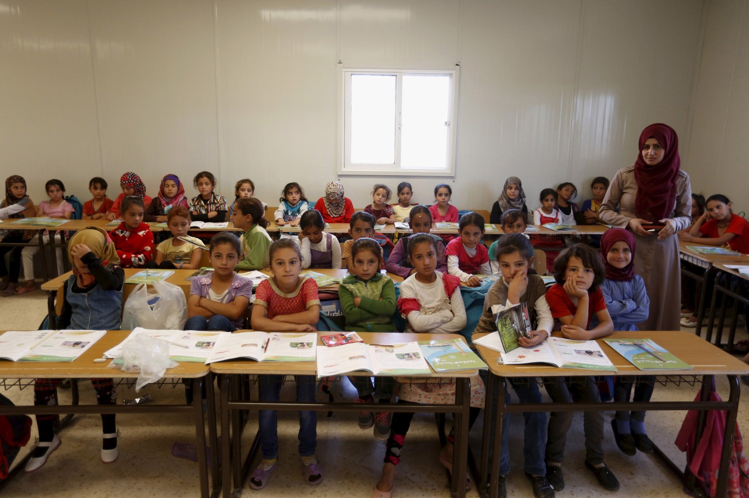 Teacher Hanan Anzi poses for a picture with Syrian refugee students inside their classroom at one of the UNICEF schools at Al Zaatari refugee camp in the Jordanian city of Mafraq, near the border with Syria, September 22, 2015. Nearly three years after Taliban gunmen shot Pakistani schoolgirl Malala Yousafzai, the teenage activist last week urged world leaders gathered in New York to help millions more children go to school. World Teachers' Day falls on 5 October, a Unesco initiative highlighting the work of educators struggling to teach children amid intimidation in Pakistan, conflict in Syria or poverty in Vietnam. Even so, there have been some improvements: the number of children not attending primary school has plummeted to an estimated 57 million worldwide in 2015, the U.N. says, down from 100 million 15 years ago. Reuters photographers have documented learning around the world, from well-resourced schools to pupils crammed into corridors in the Philippines, on boats in Brazil or in crowded classrooms in Burundi. REUTERS/ Muhammad HamedPICTURE 17 OF 47 FOR WIDER IMAGE STORY "SCHOOLS AROUND THE WORLD"SEARCH "EDUCATORS SCHOOLS" FOR ALL IMAGES - GF10000226442
