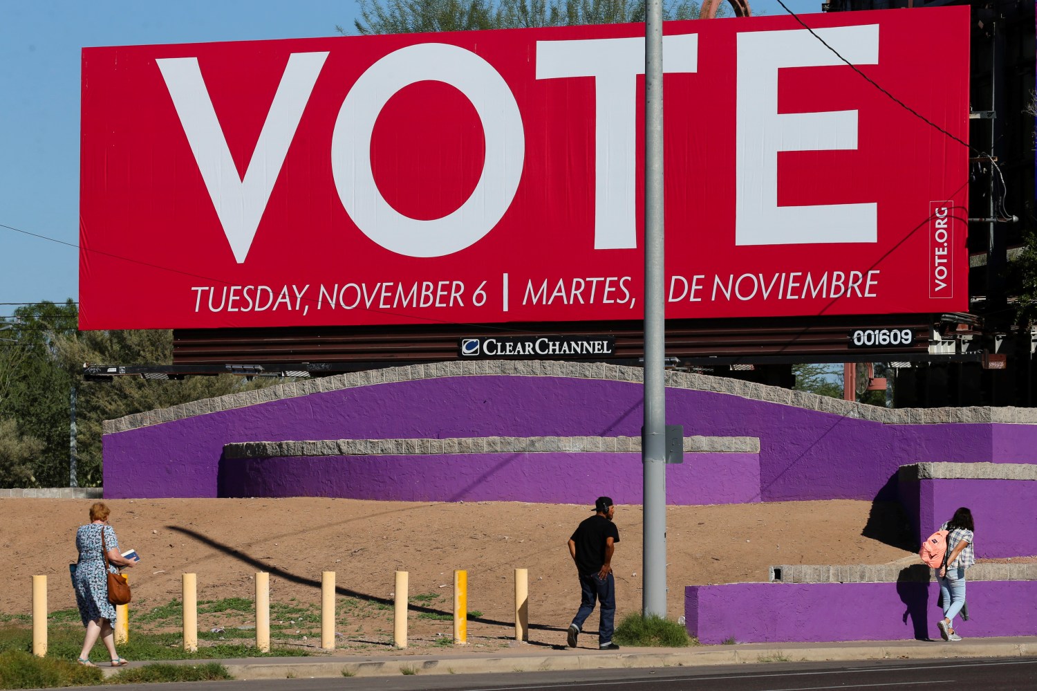 People walk under a billboard encouraging people to vote following the U.S. Midterm elections in Phoenix, Arizona, U.S. November 7, 2018.   REUTERS/Elijah Nouvelage - RC125853C7E0