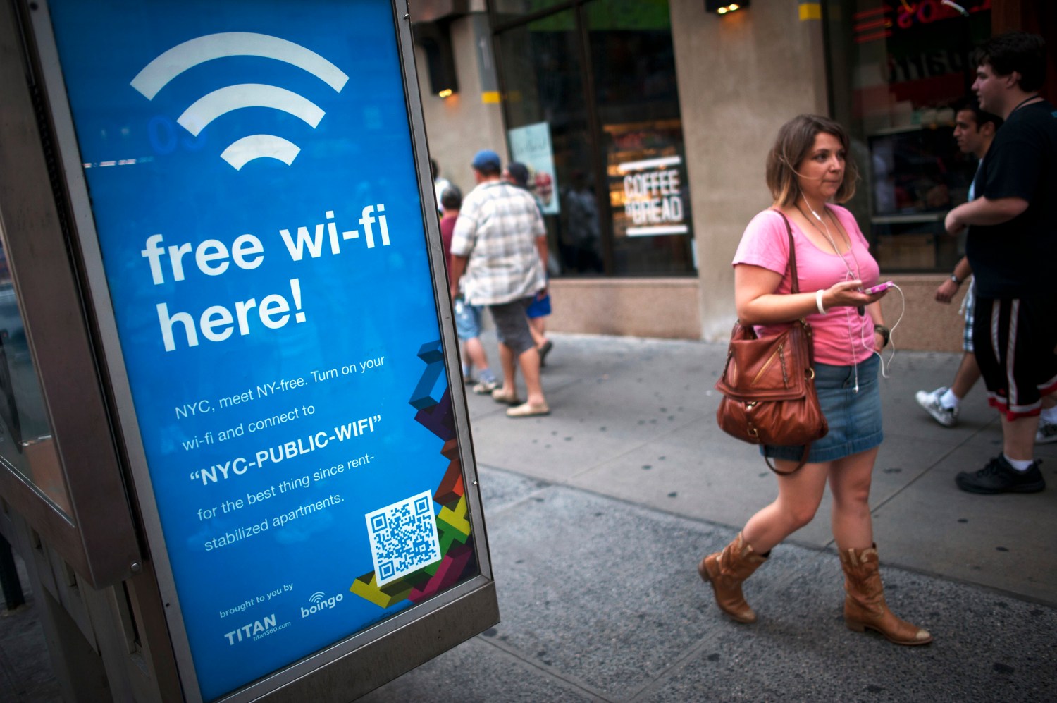 A woman walks past a WiFi-enabled phone booth in New York July 12, 2012. The New York City Department of Information Technology and Telecommunications have announced that they have converted 10 public pay phones into free WiFi hot spots as part of a pilot program to determine if it is possible to expand all city pay phones into a city-wide WiFi network. REUTERS/Keith Bedford (UNITED STATES - Tags: BUSINESS SOCIETY SCIENCE TECHNOLOGY TELECOMS) - GM1E87D0LF001