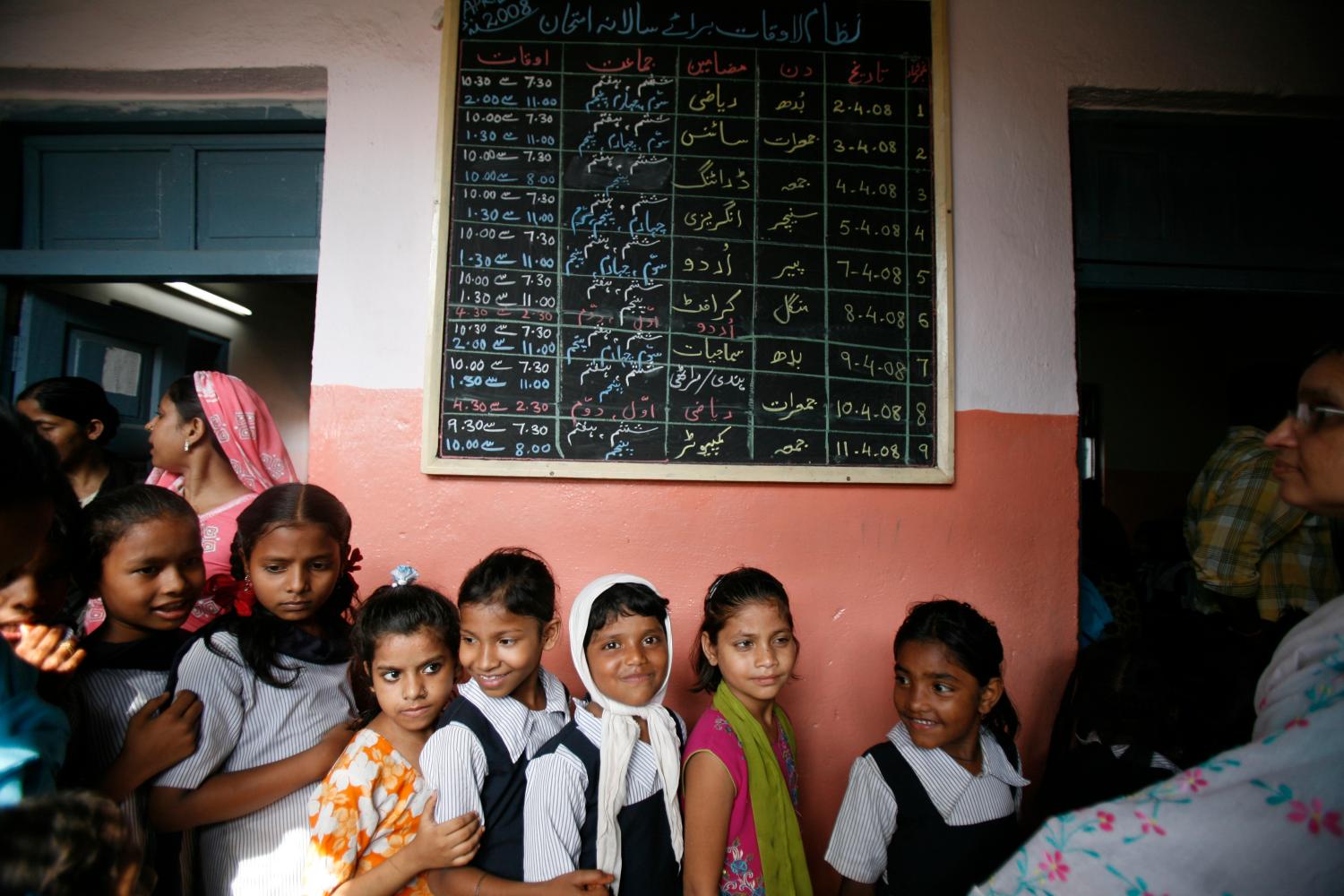 Schoolgirls queue up to receive money from authorities at a government school in Mumbai April 25, 2008. Girls attending state-run schools in India's financial capital of Mumbai are ending the school year a little richer than they began it. For each day a girl showed up in classes, city authorities are paying her 1 rupee -- about 2 U.S. cents. Boys continue to take nothing home besides their homework. Picture taken April 25, 2008 REUTERS/Punit Paranjpe (INDIA)  BEST QUALITY AVAILABLE - GF2E46U0SUZ01