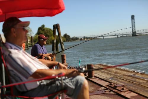 Retirees Gene Bloczynski (L) and Eric Vannieuwburg fish from a public dock on the Sacramento River in the Sacramento San Joaquin River Delta in Rio Vista, California September 4, 2013. California water officials have proposed redesigning two water diversion tunnels planned for the Delta, away from several small towns along the Sacramento River that Delta residents said would be threatened under the existing plan. Water from the tunnels would flow to urban areas in the Silicon Valley, Los Angeles and San Diego and farmers in the San Joaquin Valley. Picture taken September 4, 2013.   REUTERS/Robert Galbraith  (UNITED STATES - Tags: AGRICULTURE ENVIRONMENT SOCIETY) - GM1E99A0DRA01