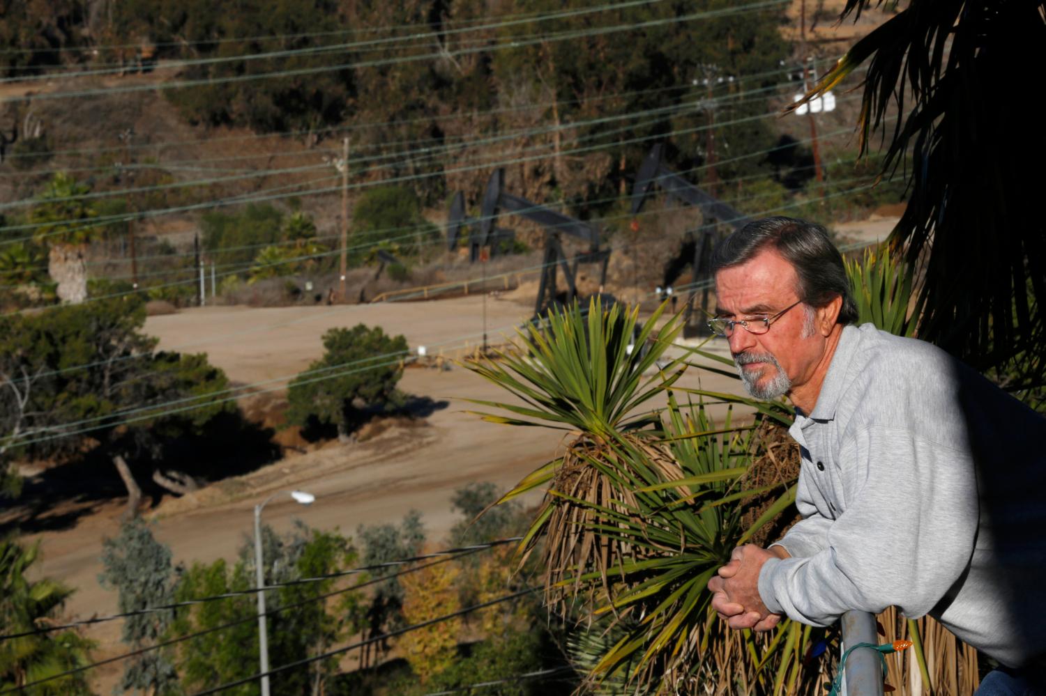 Homeowner Gary Gless leans over his balcony, as drilling wells are seen in the background, in Los Angeles, California December 11, 2013. The United States has a long history of keeping industrial activity out of middle and upper-middle-class residential neighborhoods. But that is starting to change with the spread of new technology for oil and gas drilling, such as horizontal drilling and hydraulic fracturing, or "fracking." Freeport-McMoRan, part of Freeport-McMoRan Copper & Gold Inc, said that, for the past three years, its surveys of the oilfield and surrounding communities have found no connection between its activities and "localized claims of property damage." It said it would continue to evaluate the issue. Picture taken  December 11, 2013. To match Analysis FRACKING-HOMEOWNERS/    REUTERS/Mario Anzuoni  (UNITED STATES - Tags: REAL ESTATE BUSINESS ENERGY) - GM1E9CC1QBF01