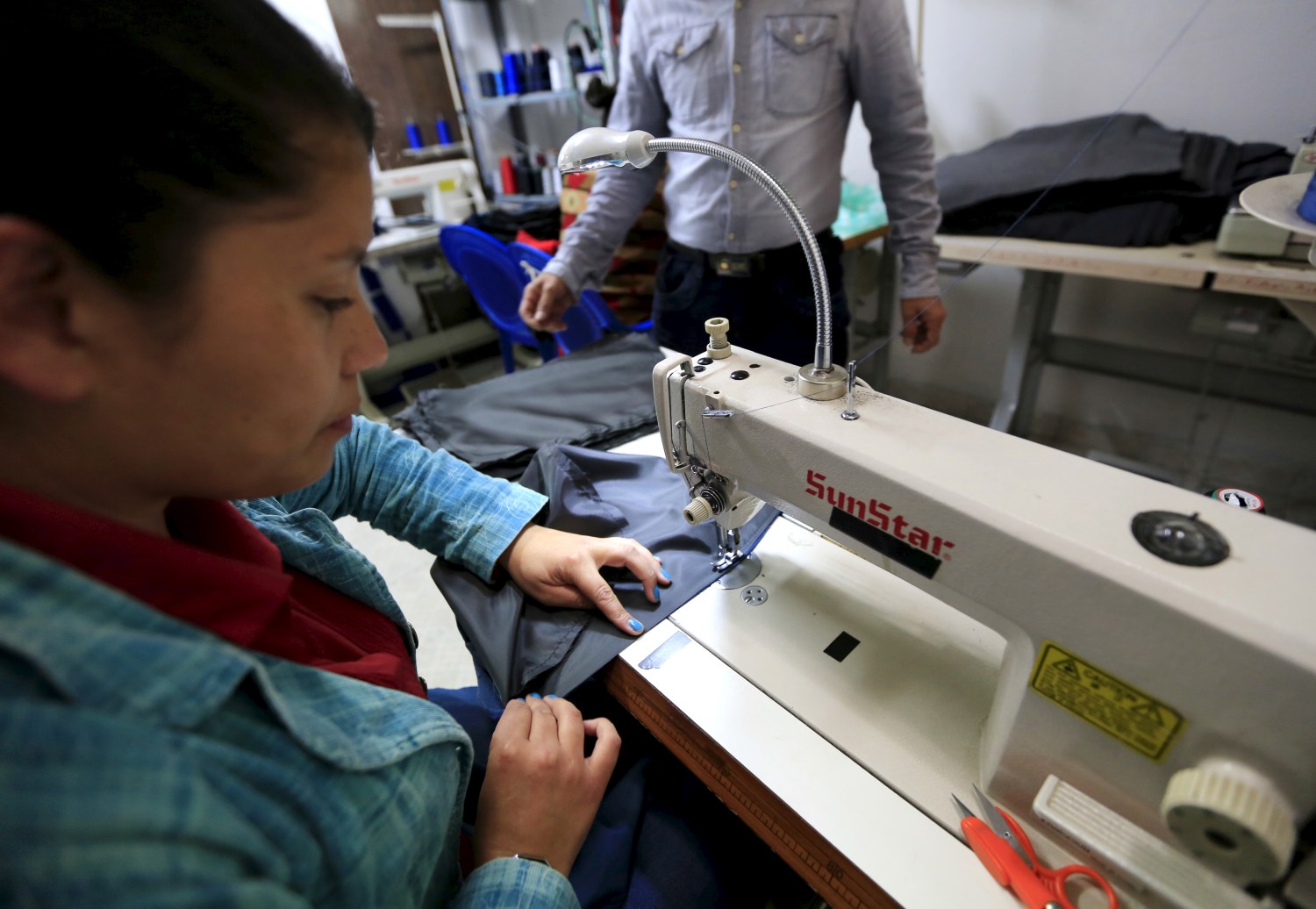 A former rebel (R), who now owns a clothing factory, oversees a worker in his workshop in Bogota in this photo taken on February 3, 2015. Fighters from the Revolutionary Armed Forces of Colombia (FARC), which is currently in peace talks with the government to end 51 years of war, face a complicated path to employment and a life away from crime as they try to reintegrate into society. Demobilized rebels are popular recruits for crime gangs and will have to overcome prejudices to become economically independent after they graduate from government reinsertion programs. Picture taken on February 3, 2015.     REUTERS/Jose Miguel Gomez - GF10000135974