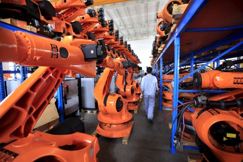 A worker walks past second-hand robots in a factory in Shanghai, August 21, 2015. More than a hundred second-hand robots used to make Audi A3s at a German car factory are going through refurbishment at a Wecan Group factory in Shanghai. Picture taken August 21, 2015. REUTERS/Aly Song  - GF10000184124