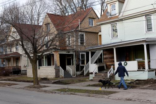 A man walks a dog past a row of vacant houses on Crandall Street, a street that became a hub for narcotics activity according to local media and police, in Binghamton, New York, U.S., April 8, 2018. Picture taken April 8, 2018. REUTERS/Andrew Kelly - RC166673BE20