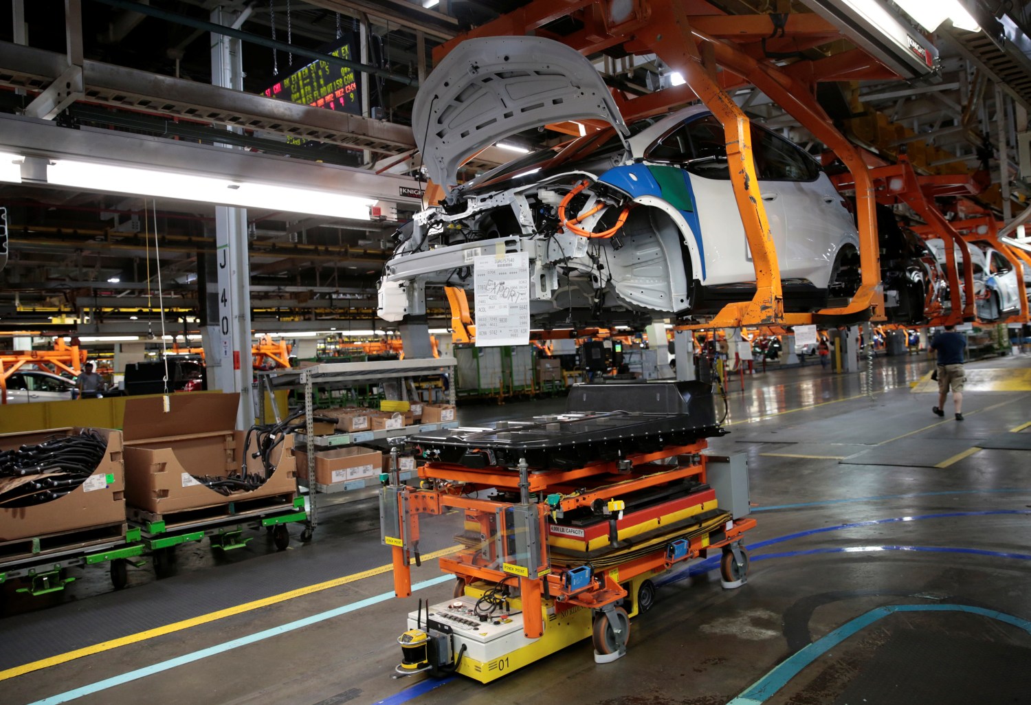 An automated guided vehicle carrying a battery pack moves under a partially assembled 2018 Chevrolet Bolt EV vehicle on the assembly line at General Motors Orion Assembly in Lake Orion, Michigan, U.S., March 19, 2018.  Photo taken March 19, 2018.    REUTERS/Rebecca Cook - RC1EEF903F10