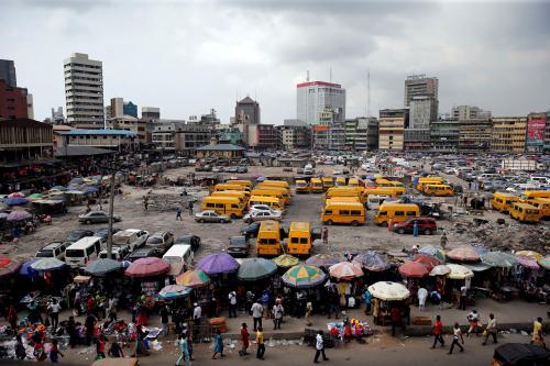 People walk past roadside stalls with umbrellas in the central business district, near Marina in Lagos, Nigeria December 13, 2016.REUTERS/Akintunde Akinleye - RC119A3413E0