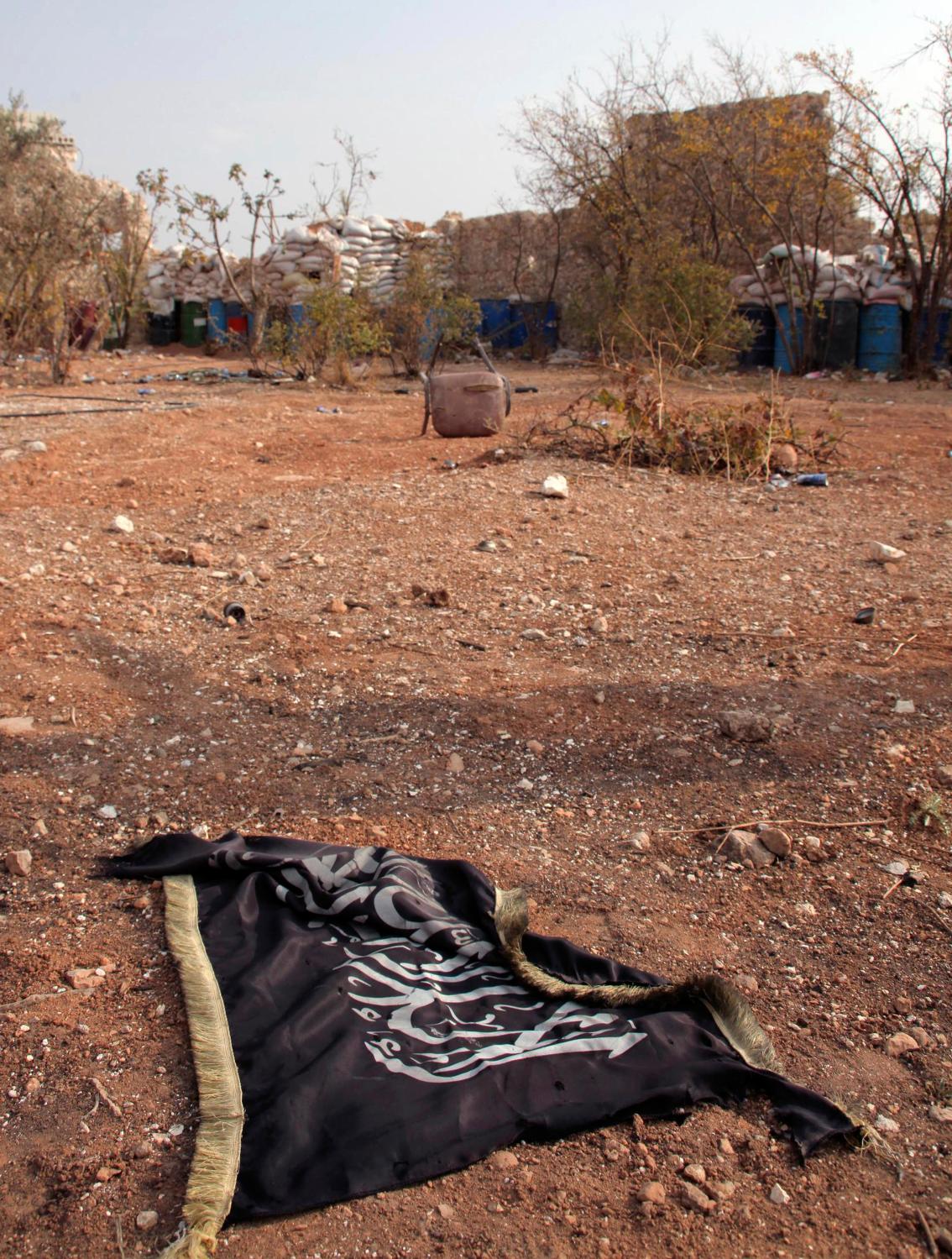 An Islamist flag is seen on the ground near the main highway leading Aleppo to Raqqa November 11, 2013. REUTERS/George Ourfalian (SYRIA - Tags: POLITICS CIVIL UNREST) - GM1E9BB1PZB01