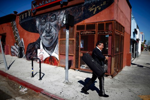 A mariachi musician walks past a mural in the Boyle Heights area of Los Angeles, home to many Mexican migrants, in California August 5, 2014. Los Angeles is a culturally thriving city and one of the most ethnically diverse in the United States, with a population that is 48.5 percent Latino and 11.3 percent Asian, according to a 2010 census. Immigration has become a hot button issue ahead of U.S. midterm elections on November 4, and despite arguments from the White House that legal migration benefits businesses, a recent opinion poll found most Americans believe migrants place a burden on the economy. Picture taken August 5, 2014. REUTERS/Lucy Nicholson (UNITED STATES - Tags: SOCIETY IMMIGRATION)ATTENTION EDITORS: PICTURE 02 OF 28 FOR WIDER IMAGE STORY 'LOS ANGELES, WORLD IN A CITY' SEARCH 'NICHOLSON CENSUS' FOR ALL - GM1EAAU16C101