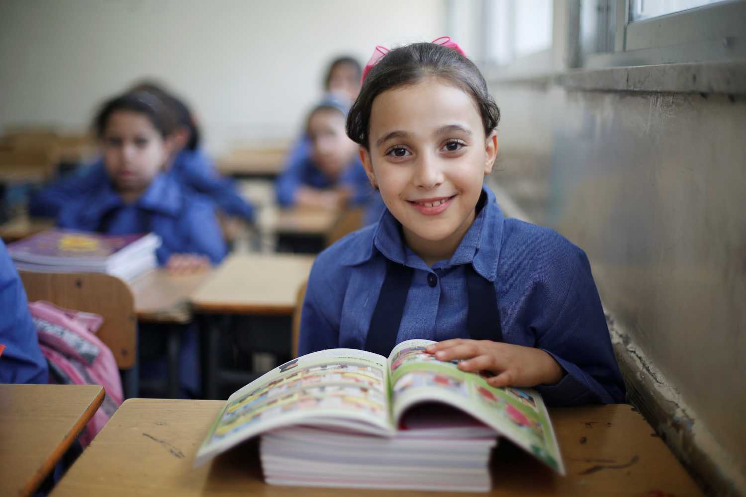 A refugee schoolchild reacts to the camera as they receive their new books on the first day of the new school year at one of the UNRWA schools at a Palestinian refugee camp al Wehdat, in Amman, Jordan, September 1, 2016.  REUTERS/Muhammad Hamed - S1AETYUGPAAA