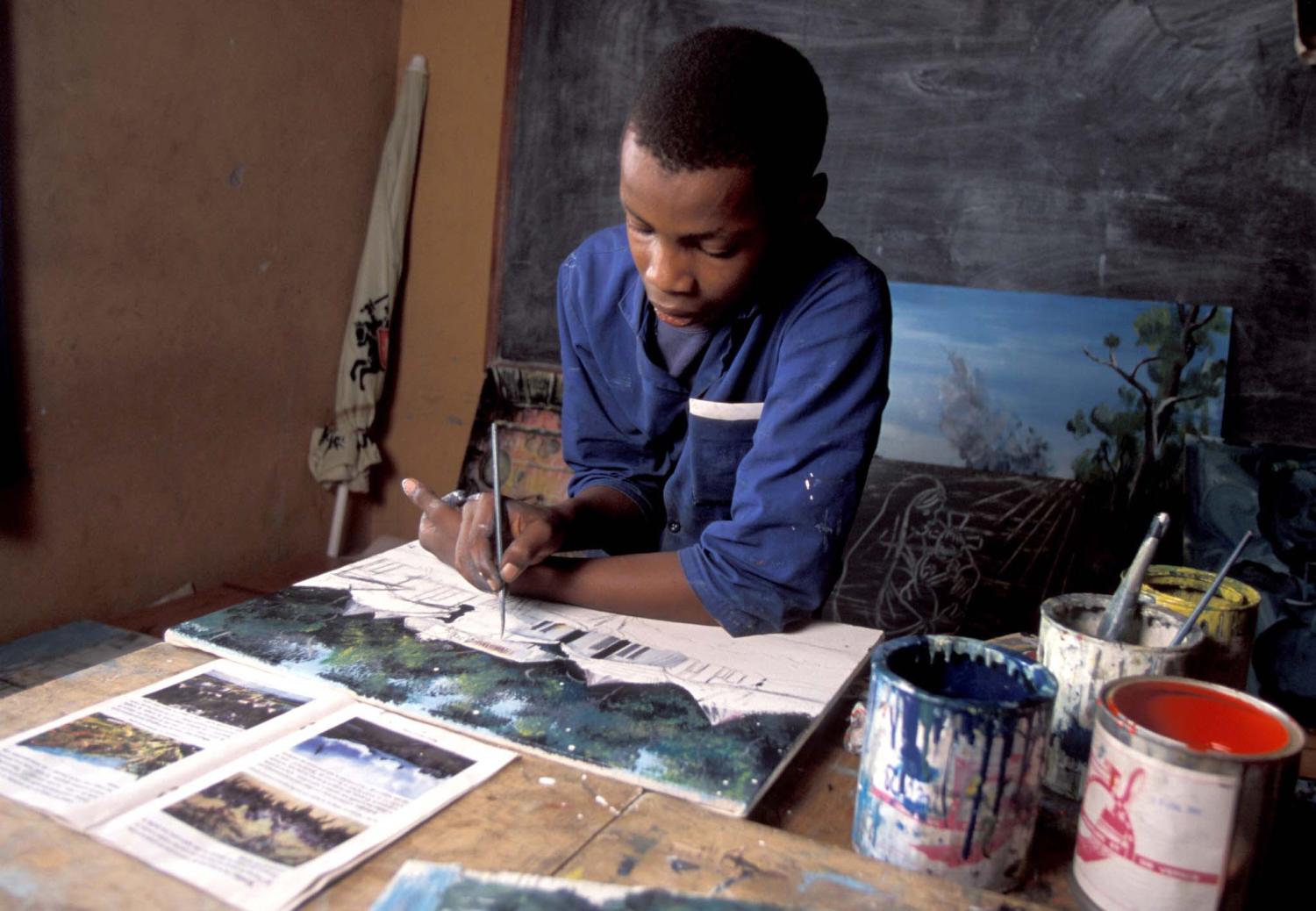 A young Rwandan boy who is an orphan and living with HIV/AIDS, paints in a classroom run by UNICEF (United nations Children's Emergency Fund) in Kigali in this undated photograph. AIDS is a big problem in Rwanda, especially after the civil war and genocide of the 1990s, and thousands of children are forced to survive on the streets. - PBEAHUKWABH