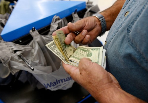 A customer counts his cash at the checkout lane of a Walmart store in the Porter Ranch section of Los Angeles November 26, 2013. This year, Black Friday starts earlier than ever, with some retailers, including Wal-Mart, opening early on Thanksgiving evening. About 140 million people were expected to shop over the four-day weekend, according to the National Retail Federation. REUTERS/Kevork Djansezian  (UNITED STATES - Tags: BUSINESS) - GM1E9BR0HYP01