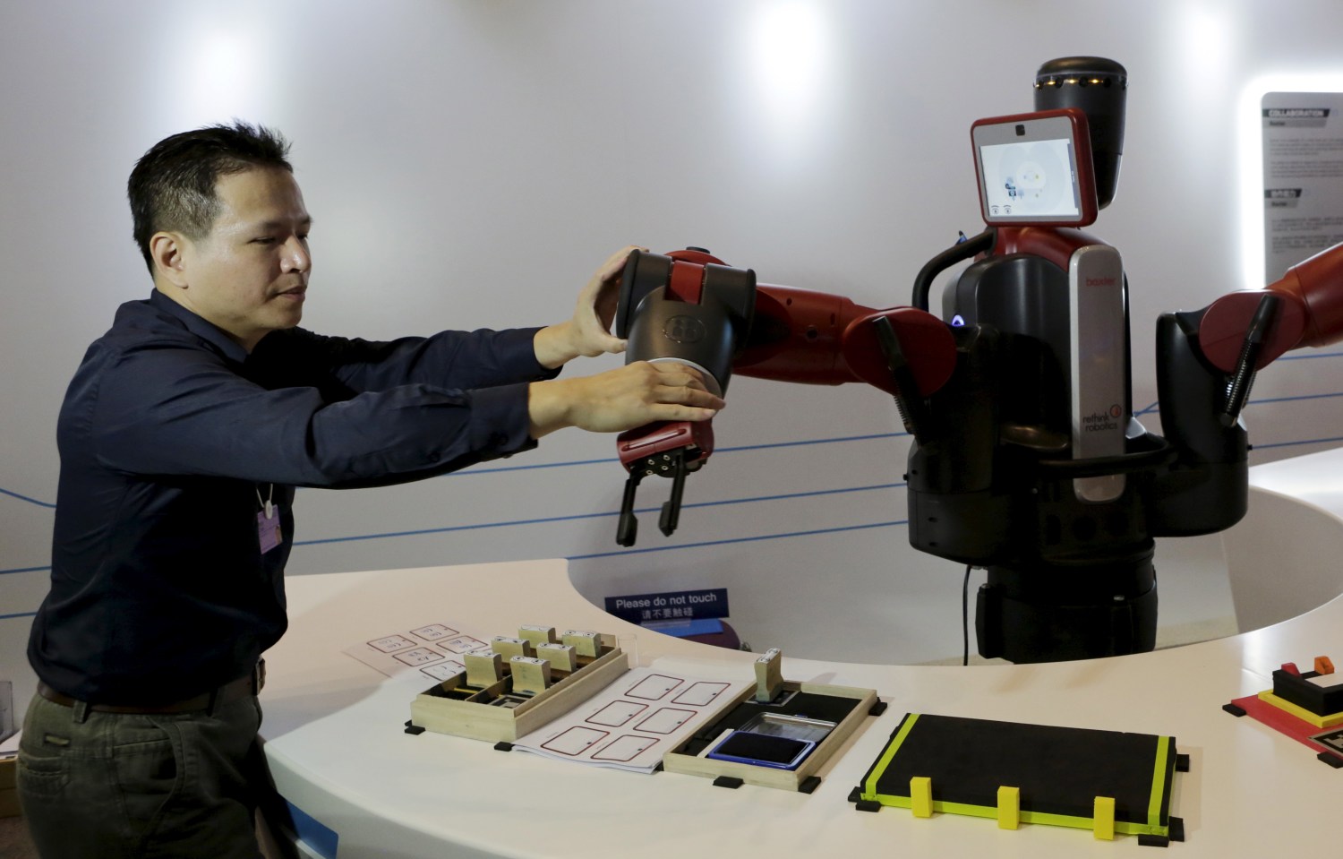 A staff member sets up the position of a mechanical hand for a Baxter robot of Rethink Robotics, during a display at the World Economic Forum (WEF), in China's port city Dalian, Liaoning province, China, September 9, 2015. Chinese robotics firms are grappling with a weakening economy and slumping automotive sector, and industry insiders already predict a market bubble just three years after the central government issued policies to spur robotics development. Picture taken September 9, 2015. REUTERS/Jason Lee  - GF10000208986