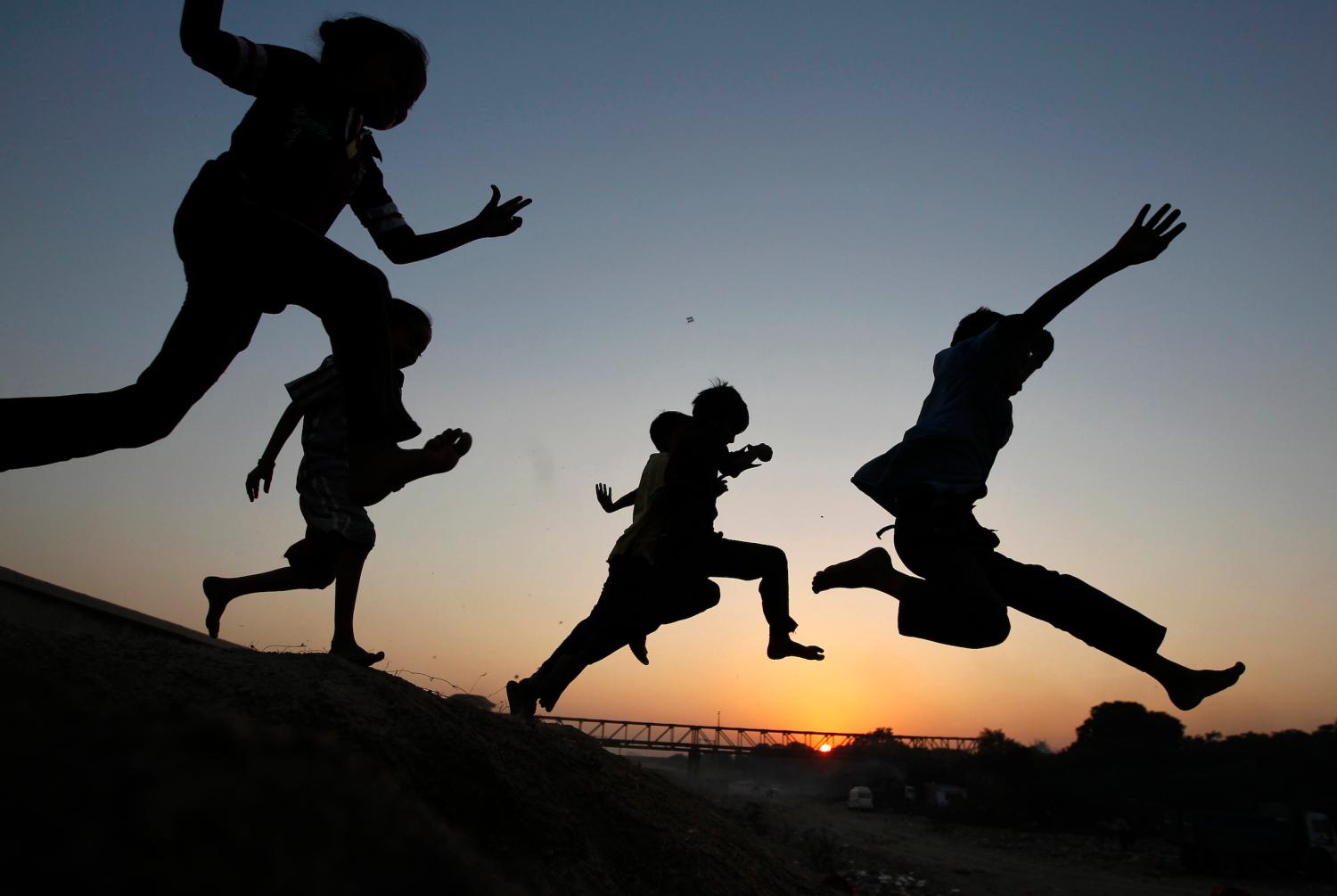Children play on a sand dune as they are silhouetted against the setting sun in the western Indian city of Ahmedabad November 28, 2014. REUTERS/Amit Dave (INDIA - Tags: SOCIETY TPX IMAGES OF THE DAY) - GM1EABS1NFQ01