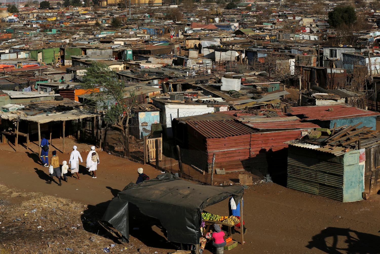 A fruit vendor (below) waits for customers at an informal settlement in Thokoza, south of Johannesburg July 18, 2014. South Africa's Reserve Bank raised interest rates for the second time this year on Thursday, with a moderate hike that struck a balance between the need to rein in inflation while allowing the economy to grow. REUTERS/Siphiwe Sibeko (SOUTH AFRICA - Tags: BUSINESS) - GF2EA7I18V601