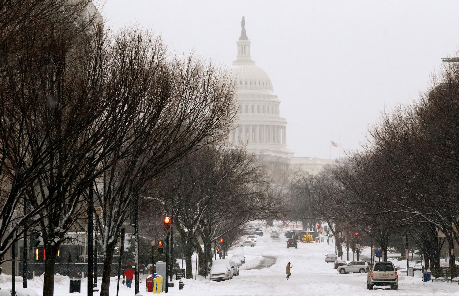 A pedestrian walks across New Jersey Avenue in front of the U.S. Capitol building, on largely deserted streets, as a major snow storm hits the Washington area, closing U.S. Federal Government offices for the day and shutting down much of the city of Washington February 13, 2014. A deadly and intensifying winter storm packing heavy snow, sleet and rain pelted a huge swath of the U.S. East Coast on Thursday, grounding flights and shuttering schools and government offices. REUTERS/Jim Bourg (UNITED STATES - Tags: ENVIRONMENT POLITICS) - GM1EA2D1QAN01