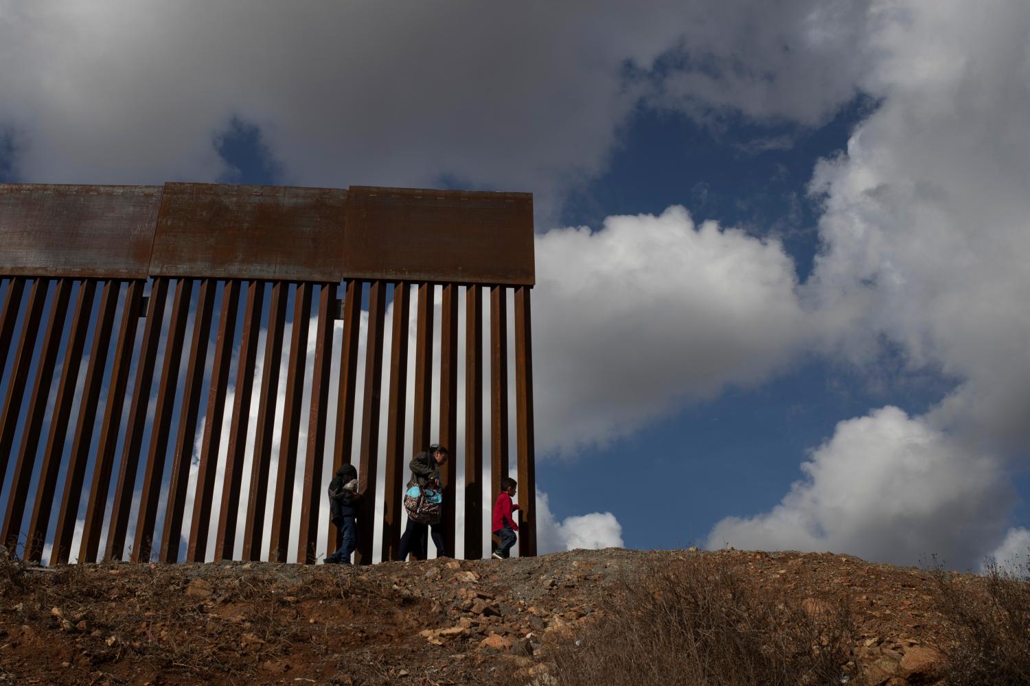 Jessica, a migrant woman from Guatemala seeking asylum, walks to the edge of the border wall before illegally crossing into the United States with her sons Francisco, 5, and Jorge, 9, from the outskirts of Tijuana into San Diego County December 1, 2018. Picture taken December 1, 2018.   REUTERS/Adrees Latif - RC1C78F00810