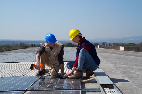 Two clean economy workers installing solar panels