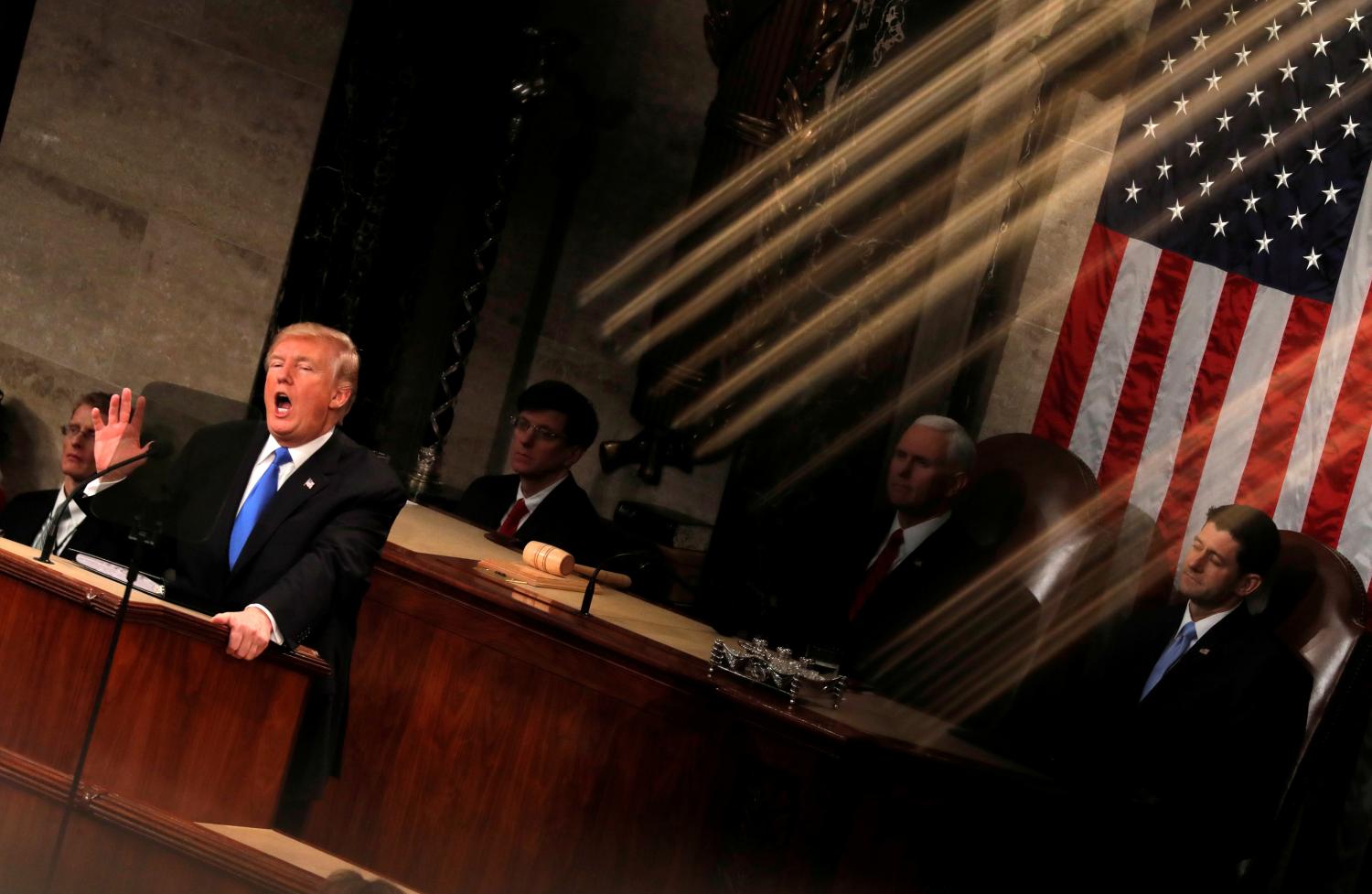 U.S. President Donald Trump and Vice President Mike Pence are seen behind the reflection of a House chamber railing as Trump delivers his State of the Union address to a joint session of the U.S. Congress on Capitol Hill in Washington, U.S., January 30, 2018. Reuters photographer Carlos Barria: "The State of the Union speech is one of the most important political events at the beginning of the year. We usually photograph it from several fixed positions, but this year I was assigned to be the 'rotating' photographer, meaning I could move around on the balcony and shoot from different angles, but only during short windows of time. During one of those windows, I found an interesting play of light reflected off a gold-colored railing, which, at a certain angle, could be seen to fall over the president." REUTERS/Carlos Barria    SEARCH "TRUMP POY" FOR FOR THIS STORY. SEARCH "REUTERS POY" FOR ALL BEST OF 2018 PACKAGES. TPX IMAGES OF THE DAY. - RC19E32723F0