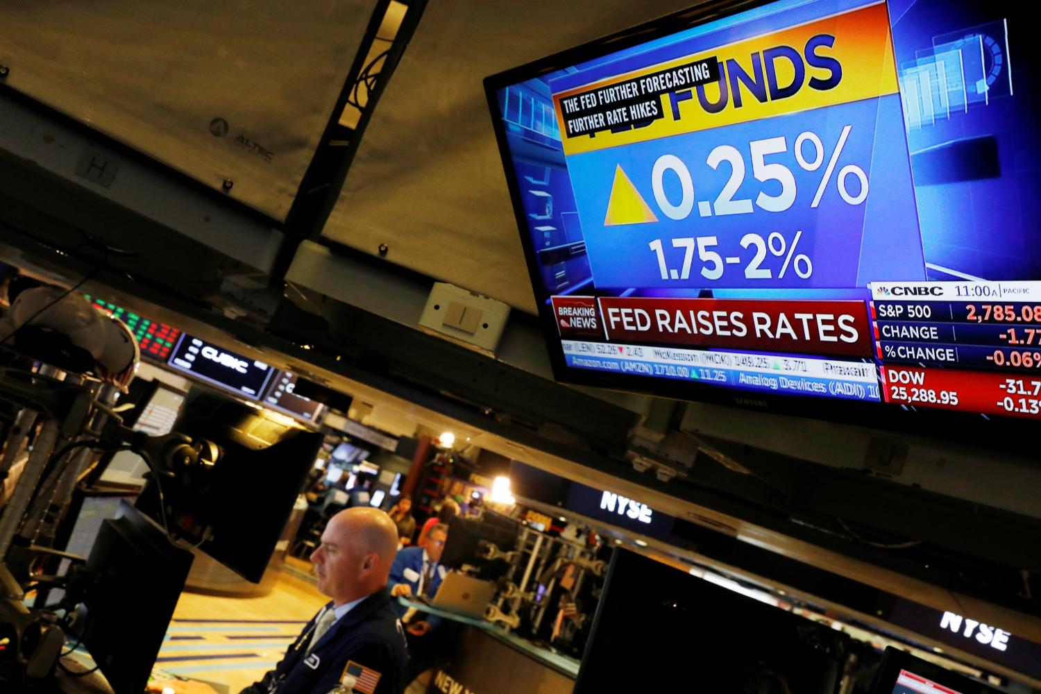 Traders work on the floor of the New York Stock Exchange (NYSE) as a TV screen shows the Fed Rate hike in New York City, U.S. June 13, 2018.  REUTERS/Brendan McDermid - RC19075F08F0