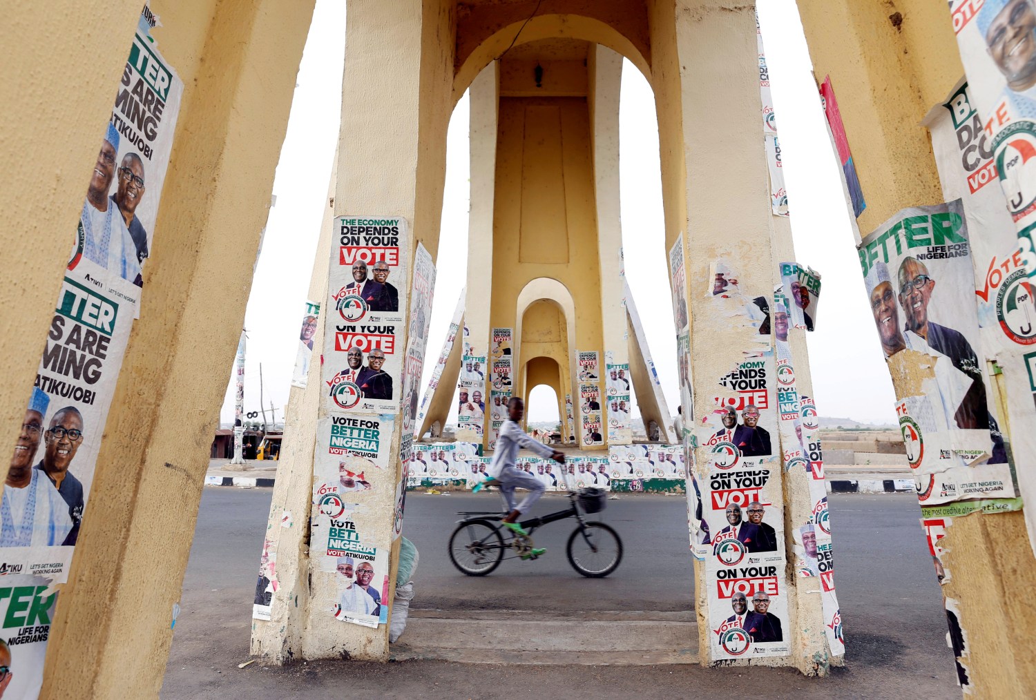 A boy rides a bicycle past a monument decorated with election posters depicting Nigeria's main opposition party presidential candidate Atiku Abubakar with his running mate, Peter Obi, in Yola, Adamawa State, Nigeria  February 26, 2019. REUTERS/Nyancho NwaNri     TPX IMAGES OF THE DAY - RC1BF60DDCA0