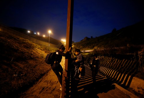 DATE IMPORTED:January 17, 2019Migrants from Honduras, part of a caravan of thousands from Central America trying to reach the United States, jump the fence to cross it illegally into San Diego County, U.S. (L), taken from the border wall in Tijuana, Mexico (R) January 16, 2019. REUTERS/Mohammed Salem