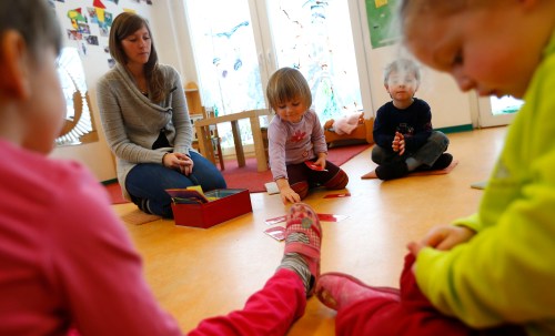 Children play with their nursery school teacher at their Kindergarten in Hanau, 30km (18 miles) south of Frankfurt, March 12, 2013. Despite a drive in German Chancellor Angela Merkel's first term to boost the number of childcare spots, Germany's birthrate remains one of the lowest in Europe.  REUTERS/Kai Pfaffenbach (GERMANY - Tags: POLITICS EDUCATION SOCIETY) - BM2E93C113J01