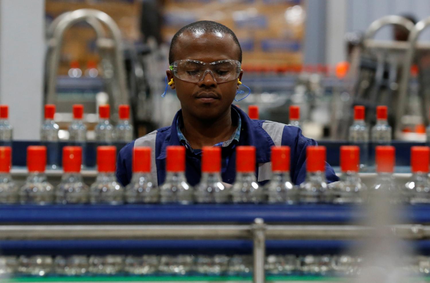 An employee inspects Kenya Cane spirit bottles on a conveyor belt at the East African Breweries Limited factory in Ruaraka factory in Nairobi, Kenya April 6, 2018. Picture taken April 6, 2018. REUTERS/Thomas Mukoya - RC18A50BF7B0