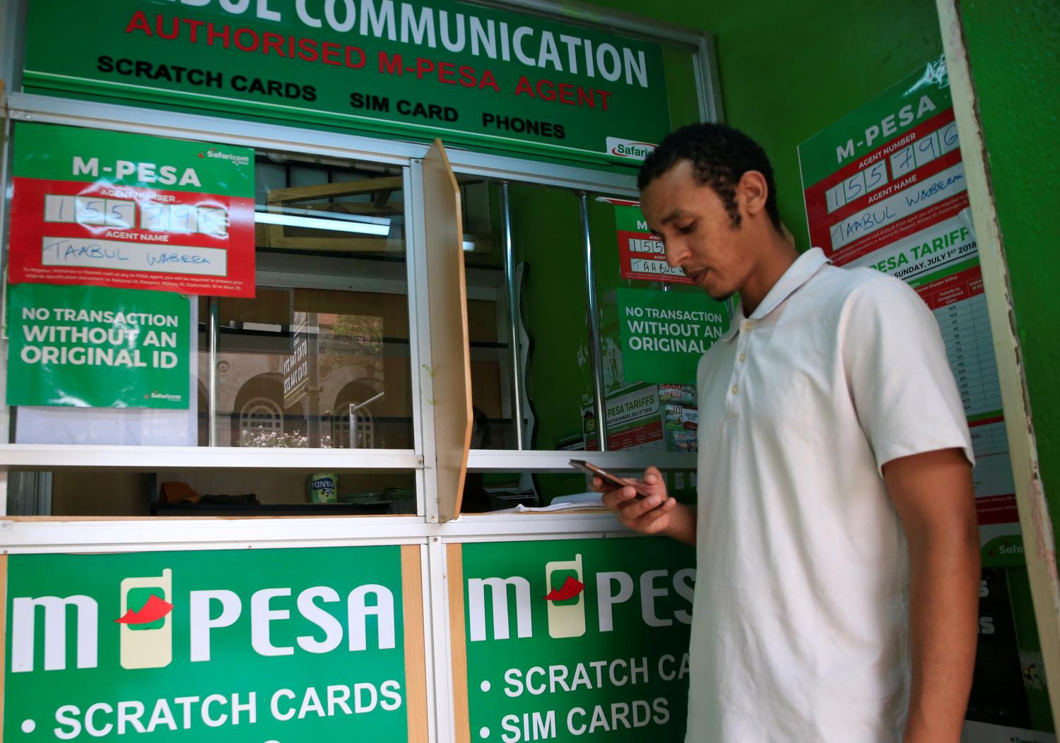 A customer conducts a mobile money transfer, known as M-Pesa, at a Safaricom agent stall in downtown Nairobi, Kenya October 16, 2018. REUTERS/Thomas Mukoya - RC13FA4477D0
