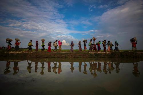 Rohingya refugees are reflected in rain water along an embankment next to paddy fields after fleeing from Myanmar into Palang Khali, near Cox's Bazar, Bangladesh November 2, 2017. REUTERS/Hannah McKay   TO FIND ALL PICTURES SEARCH REUTERS PULITZER - RC18DA7E6630