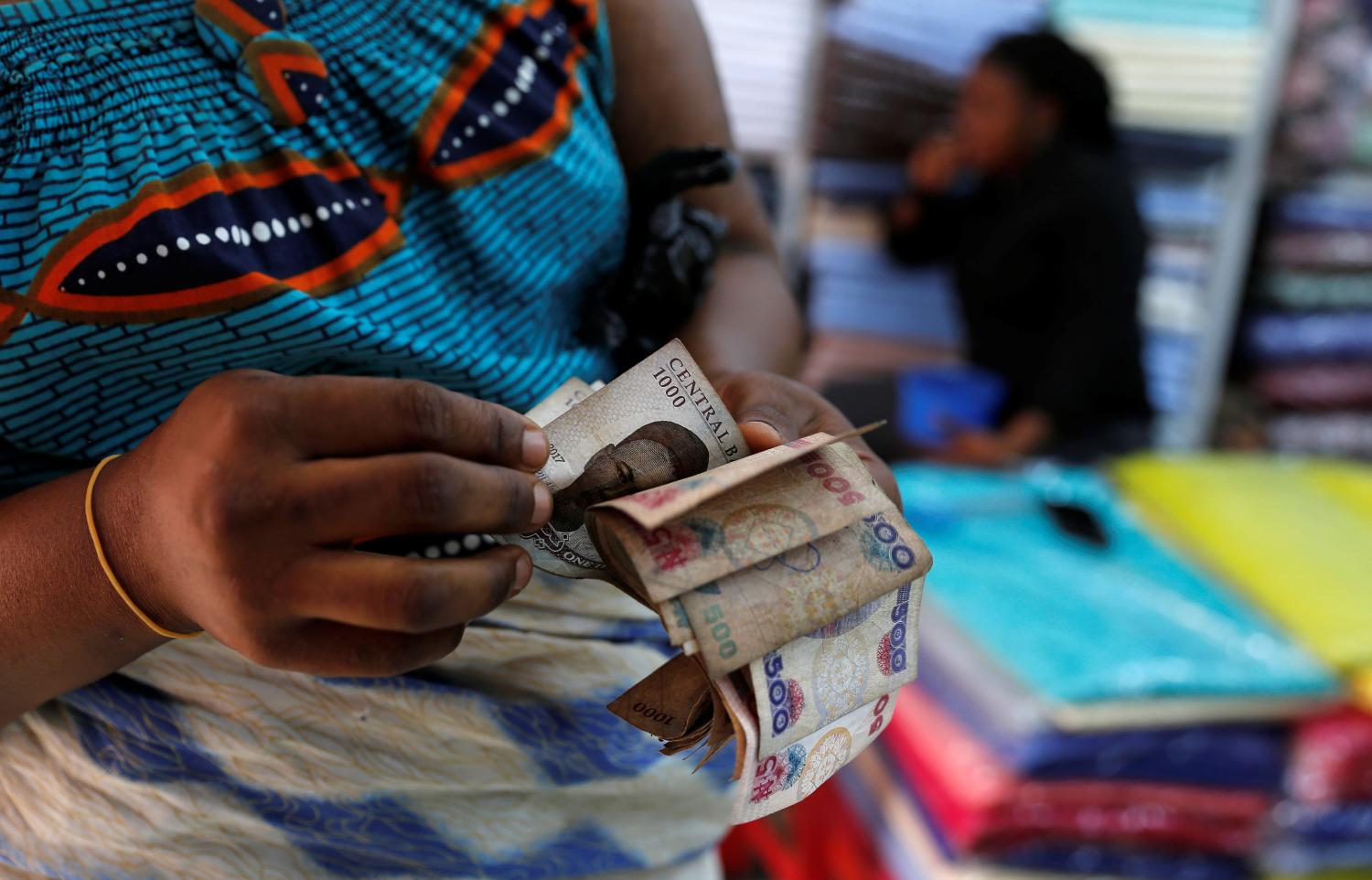 A customer counts money inside a textile shop in Idumota Market, in Nigeria's commercial capital of Lagos, Nigeria February 11, 2019. REUTERS/Nyancho NwaNri - RC1A016FA600