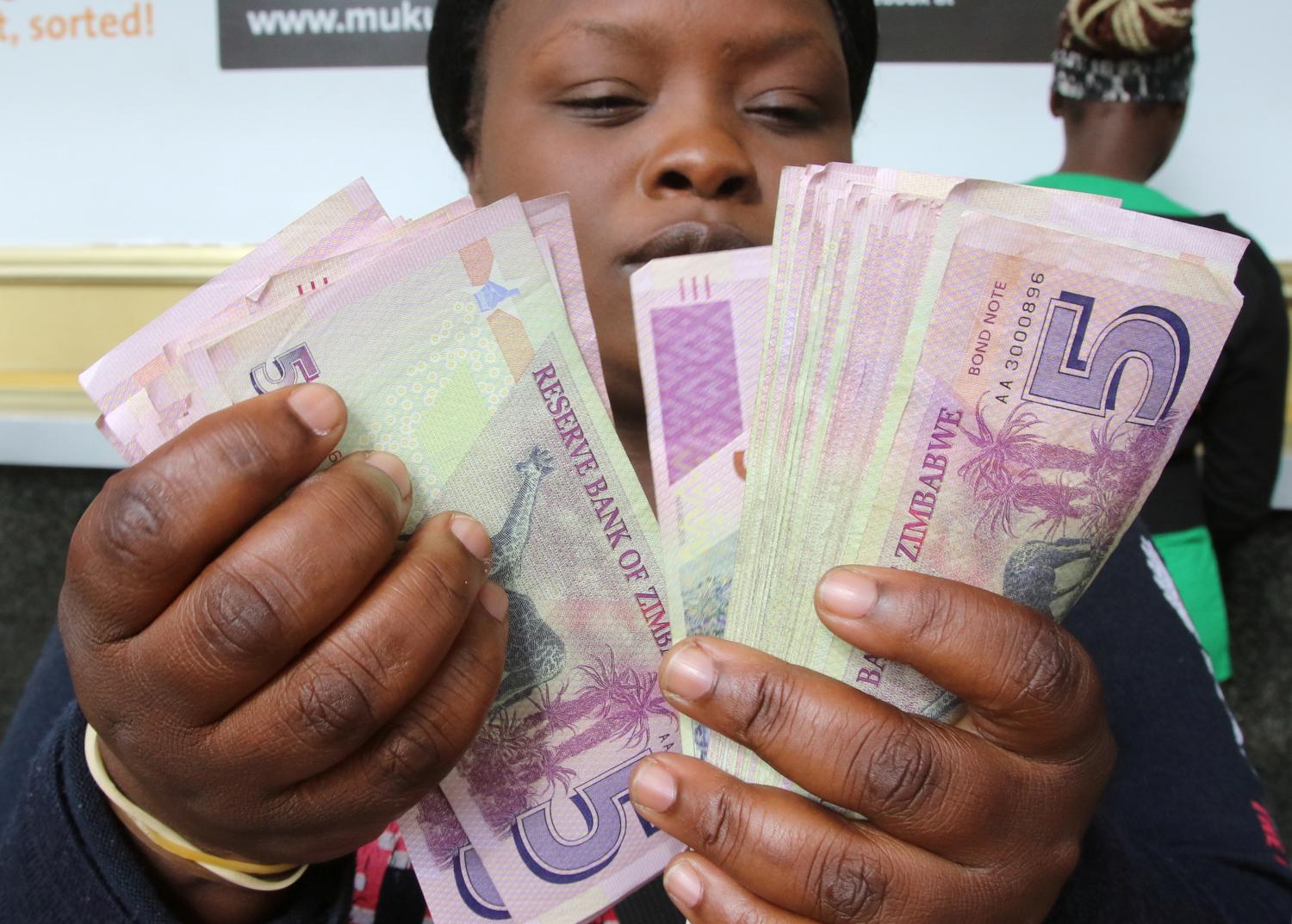 FILE PHOTO: A currency dealer counts wads of bond notes outside a bank in Harare, Zimbabwe,February 24, 2017. REUTERS/Philimon Bulawayo/File Photo - RC19BF0609A0