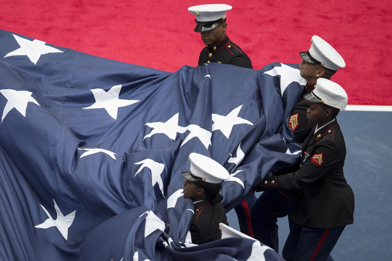 Members of the U.S. Marine Corps gather up a large U.S. flag before the Flavia Pennetta versus Roberta Vinci women's singles final match at the U.S. Open tennis tournament in New York, September 12, 2015. REUTERS/Carlo Allegri - GF10000203824