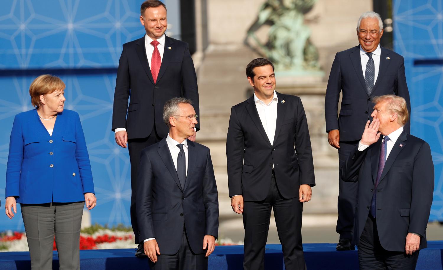 German Chancellor Angela Merkel (L) looks on as U.S. President Donald Trump speaks to other leaders as they pose for a family photo at the Park of the Cinquantenaire during the NATO Summit in Brussels, Belgium July 11, 2018. REUTERS/Kevin Lamarque - RC1E03D7E2D0