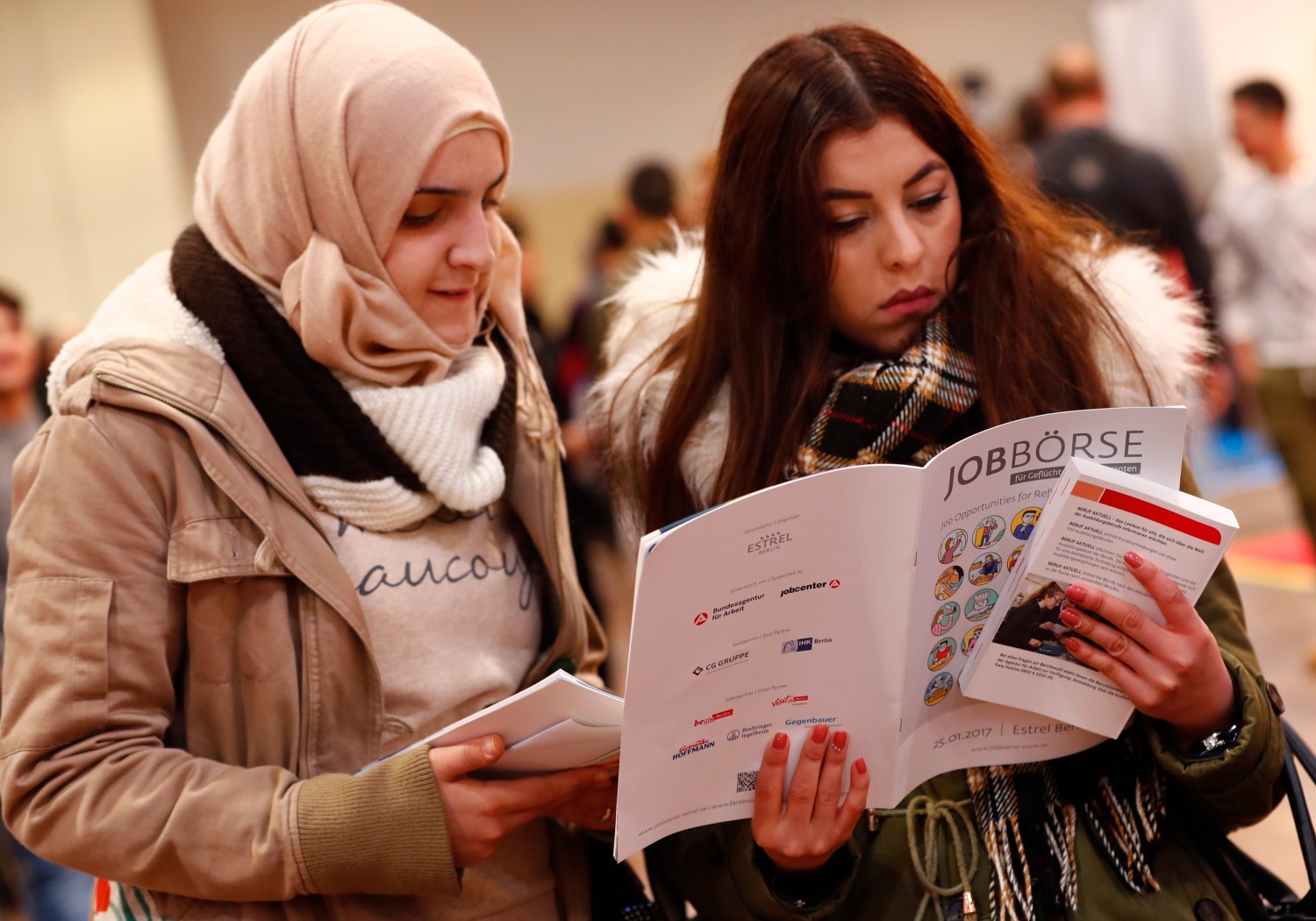 Two women visit the second job fair for migrants and refugees in Berlin, Germany, January 25, 2017.        REUTERS/Fabrizio Bensch - LR1ED1P0SO387