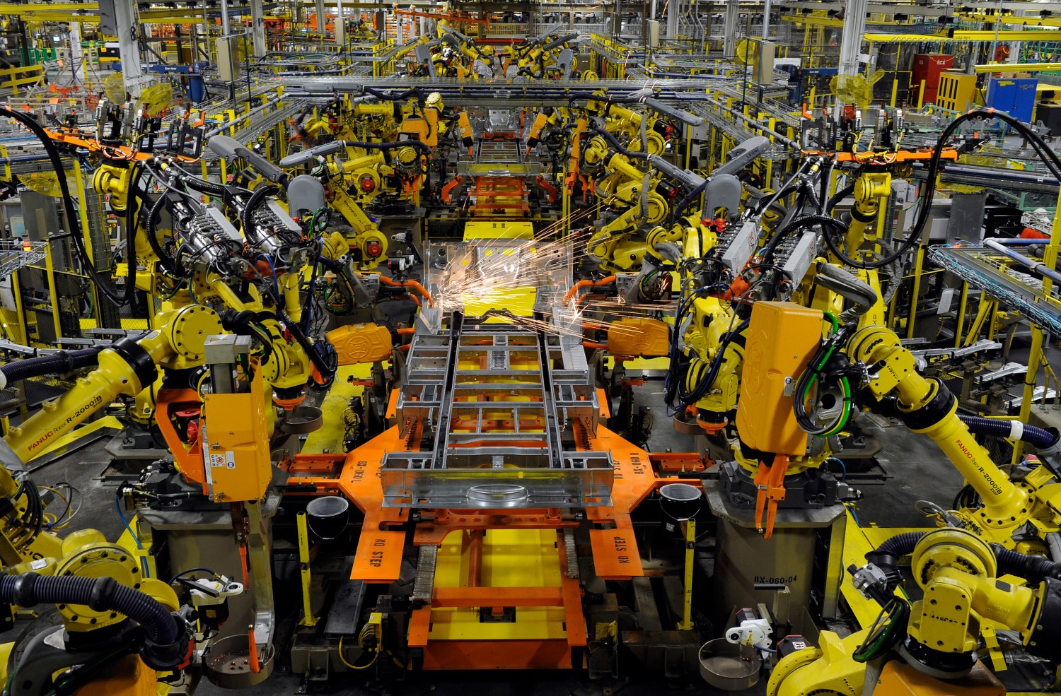Robotic arms spot welds on the chassis of a Ford Transit Van under assembly at the Ford Claycomo Assembly Plant in Claycomo, Missouri April 30, 2014.  REUTERS/Dave Kaup  (UNITED STATES - Tags: BUSINESS TRANSPORT) - GM1EA510A6N01